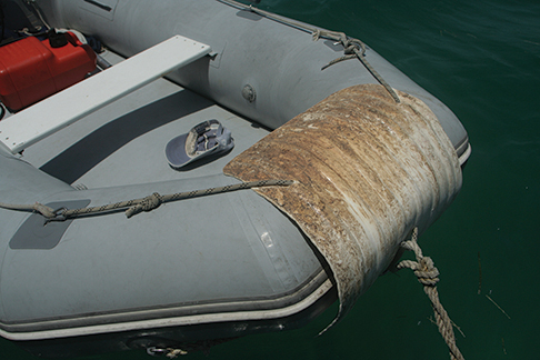 Top Photo:  Acrylic paint may help ease abrasions, but it also helps owners identify a dinghy and shields it from harmful UV rays. This Photo:  Even Captain Crunch cannot harm an old fender that has been split open and secured to the bow (or anywhere else around the dinghy).