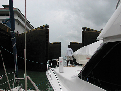 Two sailboats nested to a large sportfisher as the lock gates open