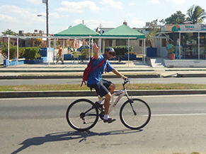 Pablo, captain of a Marlin tour boat, waves on his way to work in the Cienfuegos harbor. Bicycles are more common than cars for transportation.