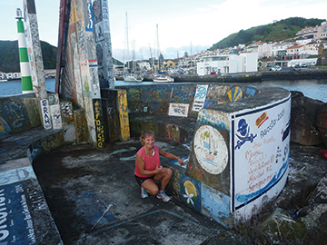 Amanda checks out what needs to be repainted on Mahina Tiare's logo on Horta marina's wall
